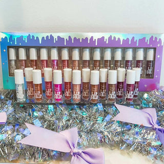 Set of lip glosses in a decorative box with tinsel and bows on a white background